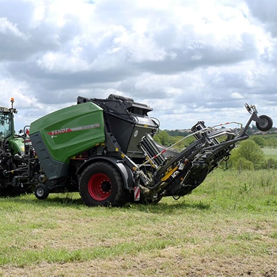 presse à balles Fendt Rotana V attelée à un tracteur fendt dans un champs